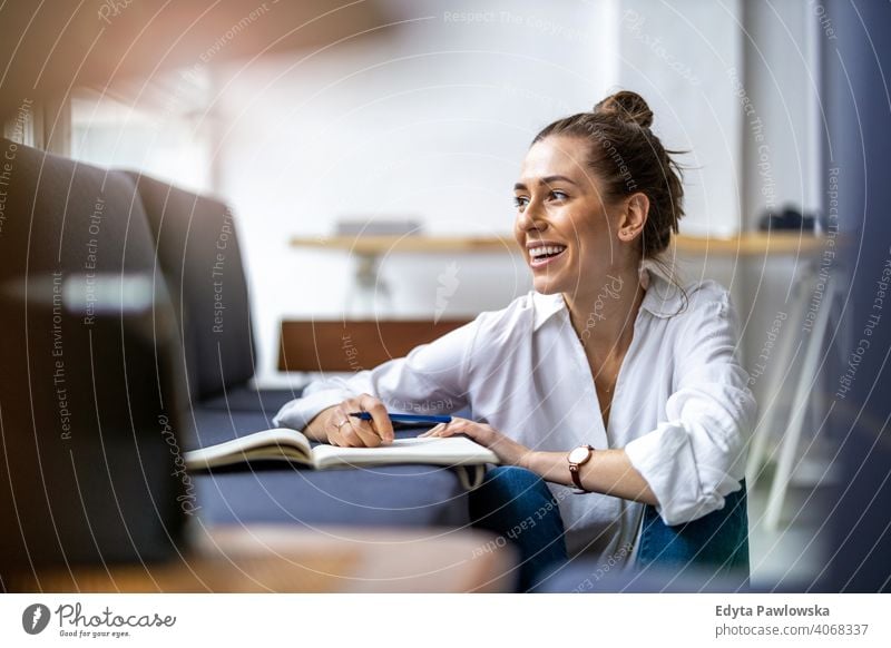 Young woman doing homework on sofa sitting couch resting relaxing comfortable millennials student hipster indoors loft window natural girl adult one attractive