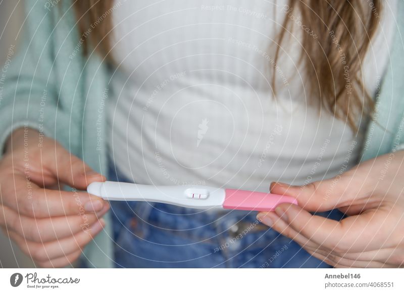 Happy young woman holding a positive pregnancy test close-up bright colors modern stylish design pregnant result female fertility motherhood maternity adult