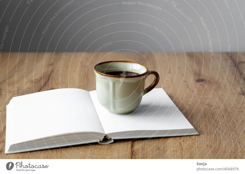 A rustic coffee cup on an open book Coffee Cup Book Open Beverage Coffee break Breakfast Aromatic Morning Hot Brown Old Caffeine Espresso Table Enamel Black