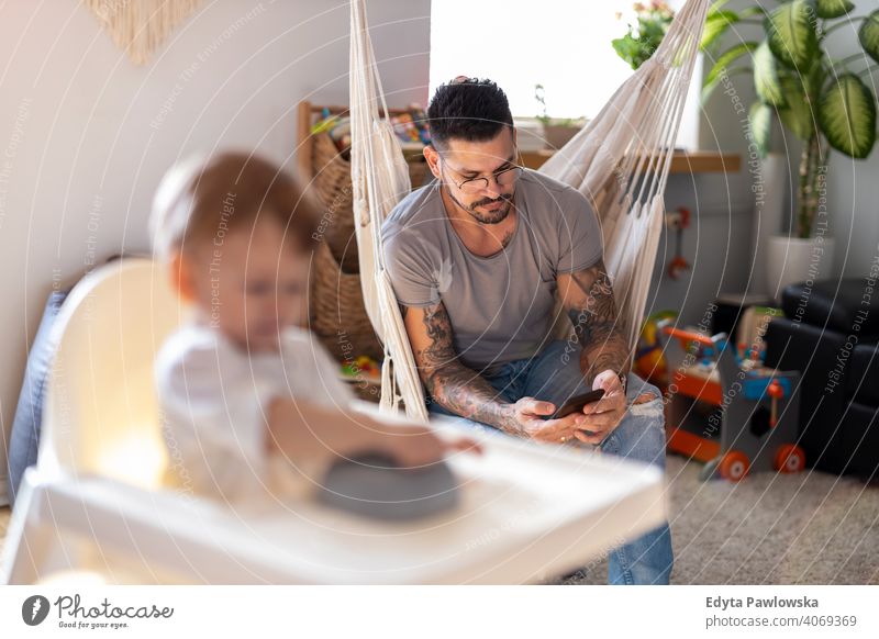 Stay at home dad on smartphone ignoring child single parent single dad fathers day fatherhood stay at home dad paternity leave modern manhood family son house