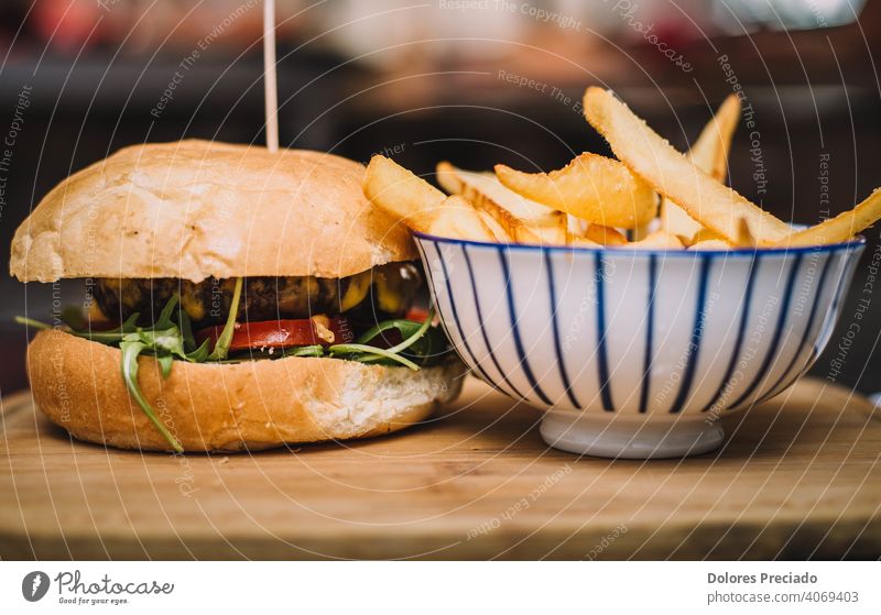 Beef burger with cheddar cheese and artisan bread, stuffed with tomato, arugula, mayonnaise. Cholesterol table board ketchup isolated copy space comfort food