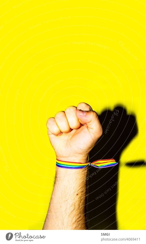 A man's fist held high with a bracelet in the colors of the gay flag. celebrate celebration colorful colour community discrimination diversity equal equality