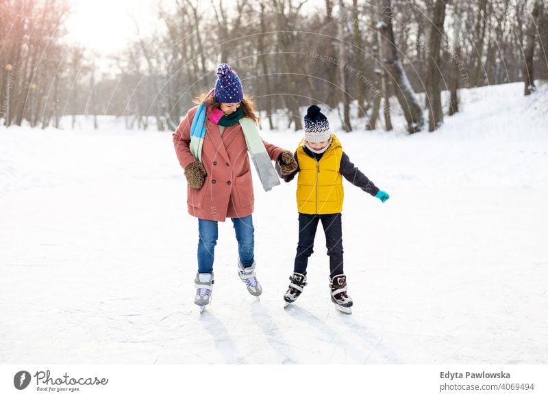 Mother and son ice-skating on frozen pond mother daughter season together cheerful fun kid people park holiday forest childhood woman girl nature joy snow cold