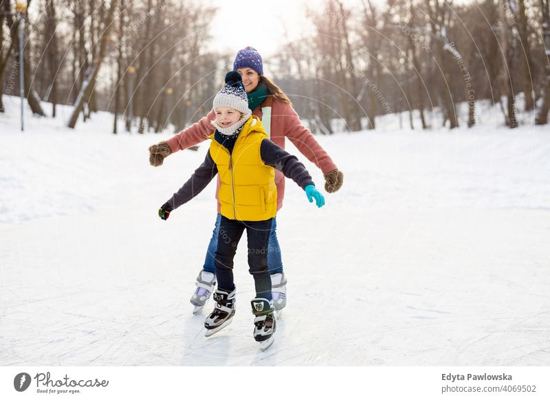 Mother and son ice-skating on frozen pond mother daughter season together cheerful fun kid people park holiday forest childhood woman girl nature joy snow cold