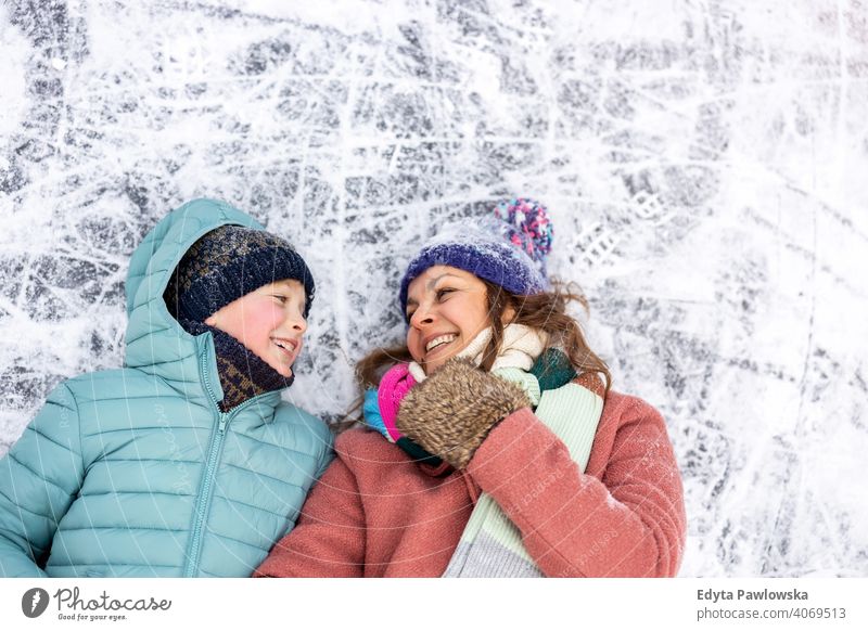 Mother and son lying down on frozen lake surface and smiling mother daughter season together cheerful fun kid people park holiday forest childhood woman girl