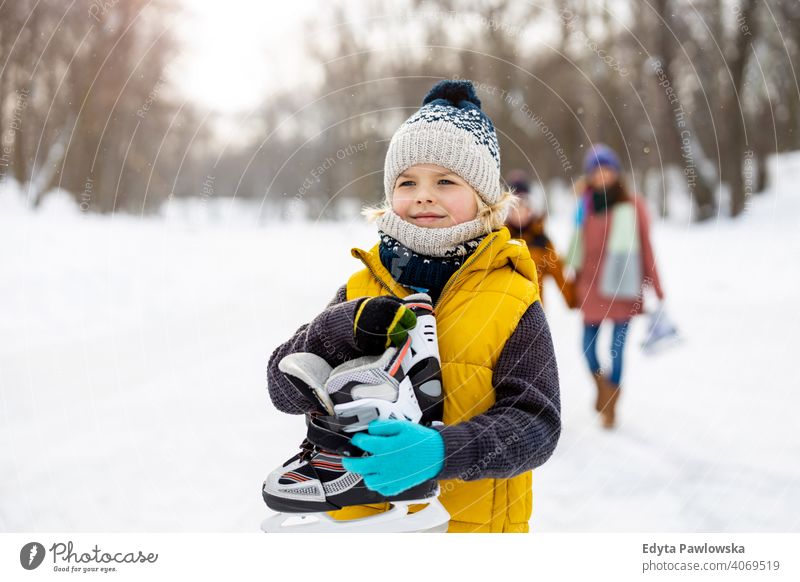 Little boy going ice skating with his family mother son daughter season together frozen cheerful fun kid people park holiday forest childhood woman girl nature