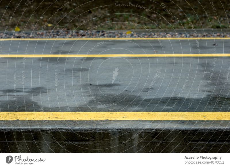 Yellow lines and arrows on a wet concrete path in the park. asphalt background black city dark day direction drive grey guidance highway indicate journey lane