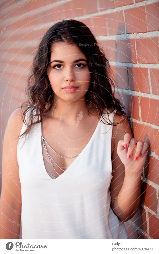 Happy brunette girl with red wall brick of background young sunny beautiful hair summer people beauty portrait natural fashion female sunshine yellow lifestyle