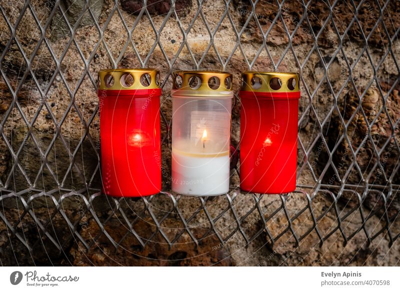 Close-up photo for set of three red white red burning candles at memorial event in Riga, Latvia representing Latvian flag colours at fired background