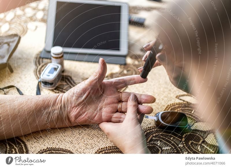 Cropped shot of a nurse doing glucose blood test on senior patient during home visit real people candid genuine woman mature female Caucasian elderly house old