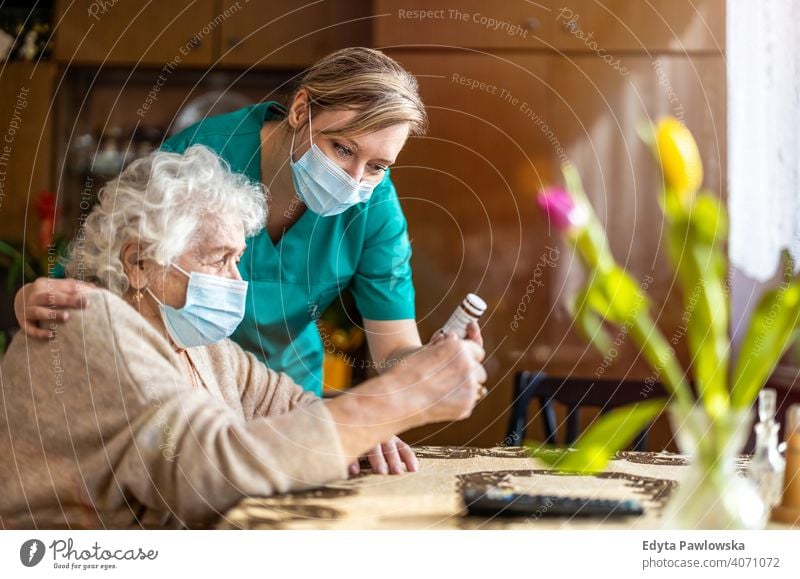 Senior woman visited by home care specialist during lockdown coronavirus face mask real people covid senior nurse elderly candid genuine mature female Caucasian