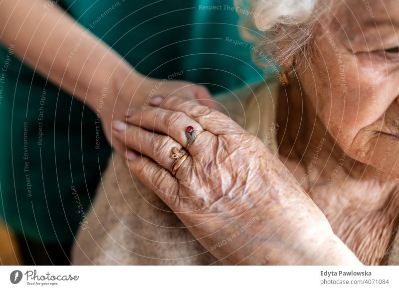 Cropped shot of a senior woman holding hands with a nurse consoling wrinkled real people candid genuine mature female Caucasian elderly aging grandmother