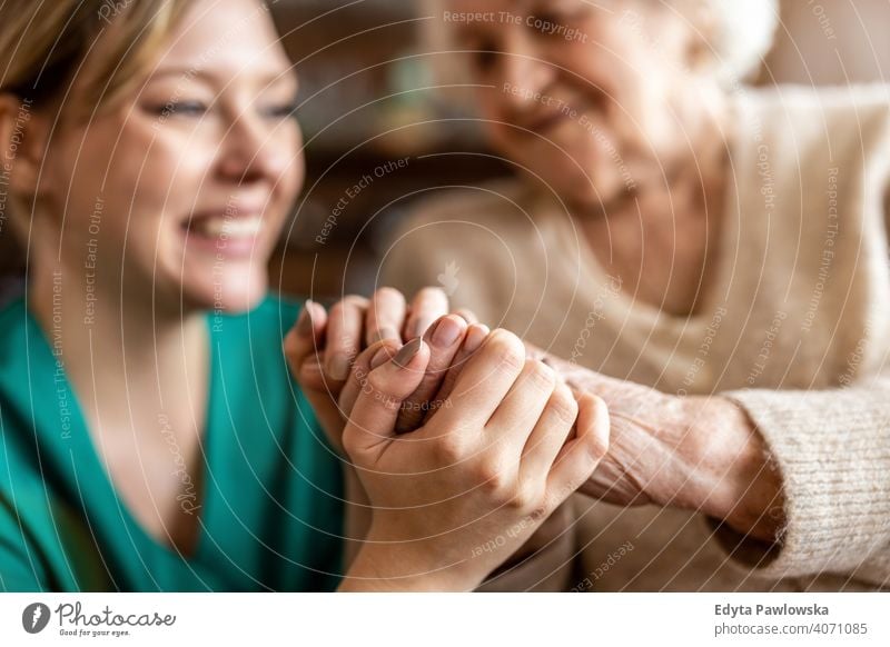 Cropped shot of a senior woman holding hands with a nurse consoling wrinkled real people candid genuine mature female Caucasian elderly aging grandmother