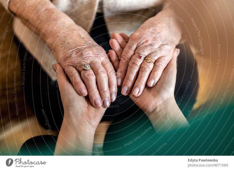 Cropped shot of a senior woman holding hands with a nurse consoling wrinkled real people candid genuine mature female Caucasian elderly aging grandmother