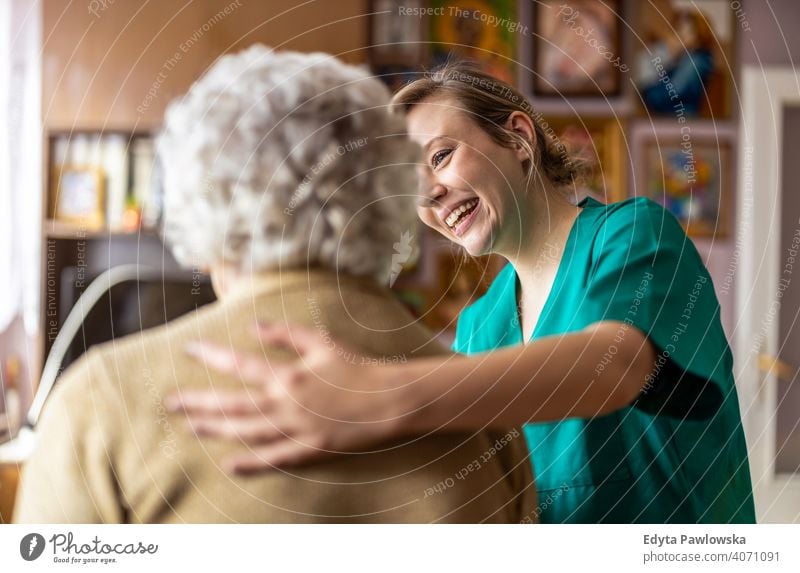 Friendly nurse supporting an elderly lady real people candid genuine woman senior mature female Caucasian home house old aging domestic life grandmother