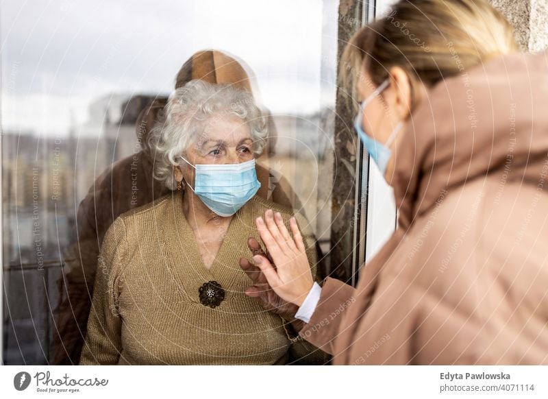 Woman visiting her grandmother in isolation during a coronavirus pandemic window covid lockdown looking quarantine looking through window social distancing