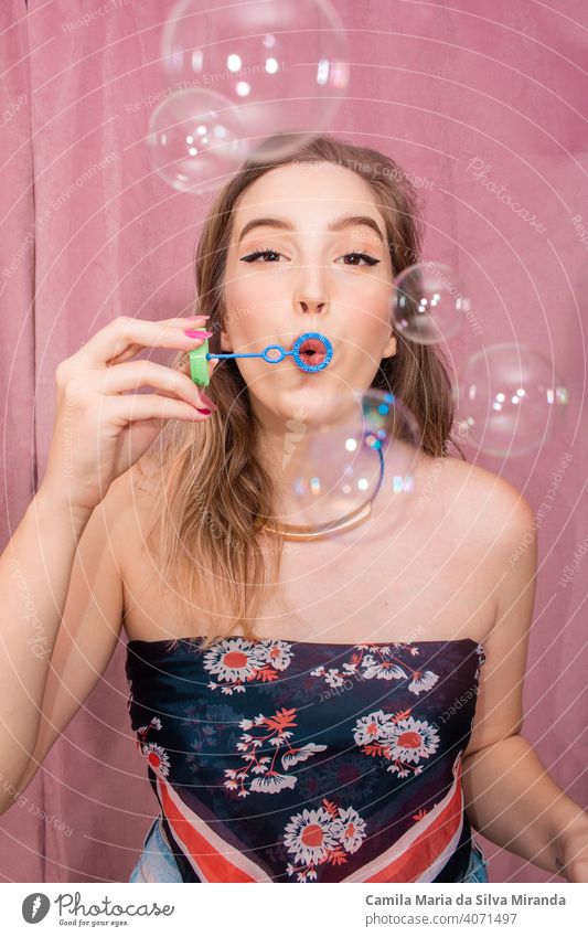 Happy woman making soap bubbles with pink background. adorable beautiful birthday celebration cheerful emotion emotions face fashion female funny girl glamour