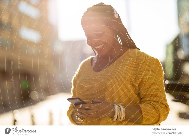 Young woman with smartphone in an urban city area one person alone outdoors day positivity confident carefree people young adult casual beautiful attractive