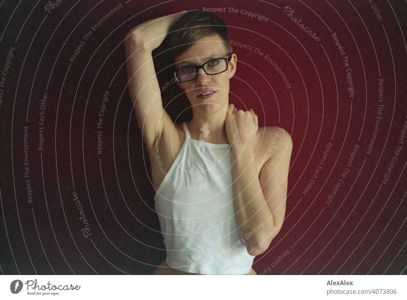 Analogue portrait with expired 35mm film of a young woman in front of a red wall Woman Young woman Slim Top Eyeglasses sits Skin Large Athletic Articulated