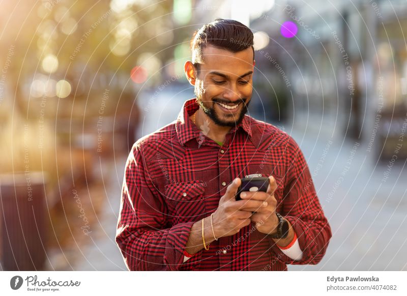 Young man walking on the street and text messaging Sinhalese asian Indian bearded outside urban standing outdoors city Warsaw one casual lifestyle guy