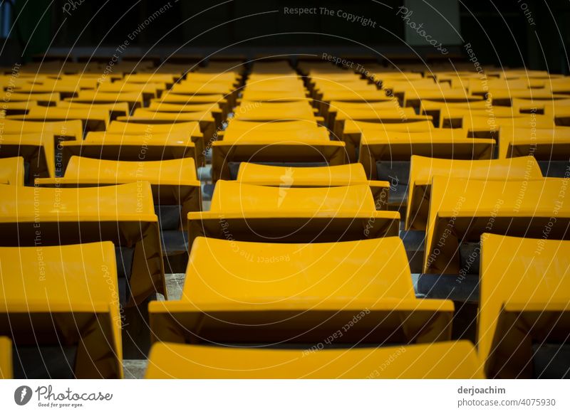 Quite a few chairs are still free The curtain is still closed. The play has not yet begun. The audience is about to arrive. The stage is still dark. Only the chairs in the wide round are illuminated by the sun.