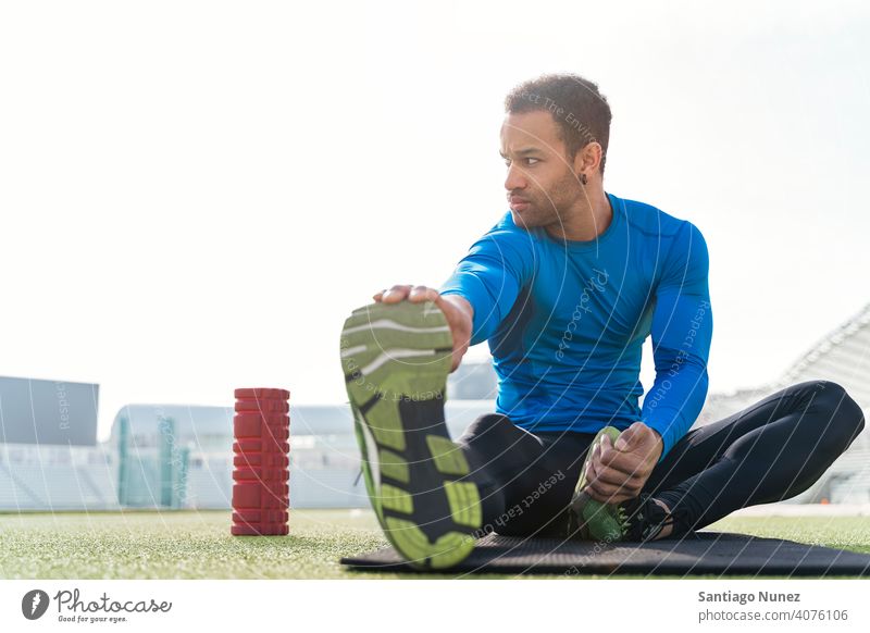 Black Athlete Stretching in Sports Track stretch stretching black man african american foam roller sitting athlete runner legs sports track focus trainers