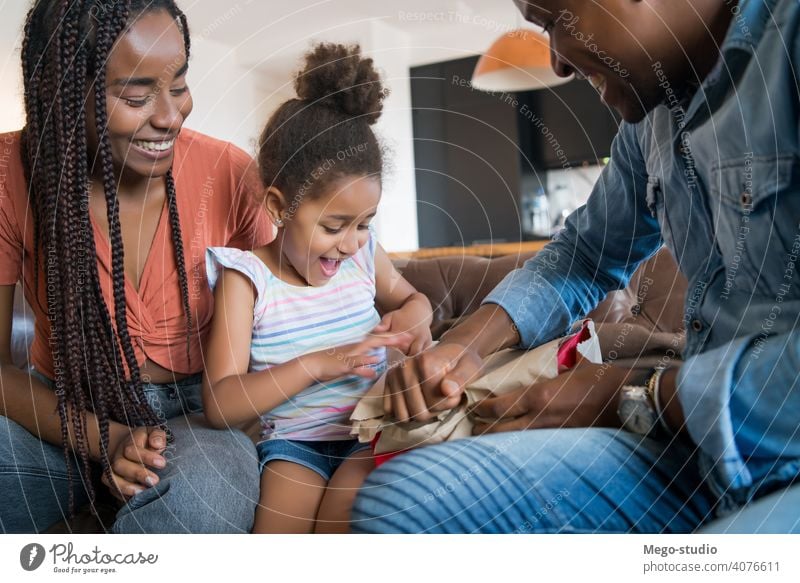 Little girl receiving gift from her parents. happy family surprise cheerful home together celebration present lifestyle celebrate celebrating surprised smiling