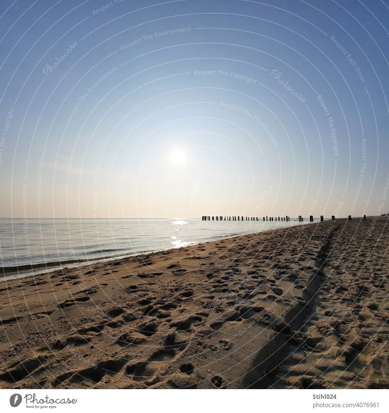 Sandy beach with groyne in the afternoon Beach stroll Baltic Sea North Sea footprints Tracks Break water Swell Sun Horizon vacation reflection Ocean