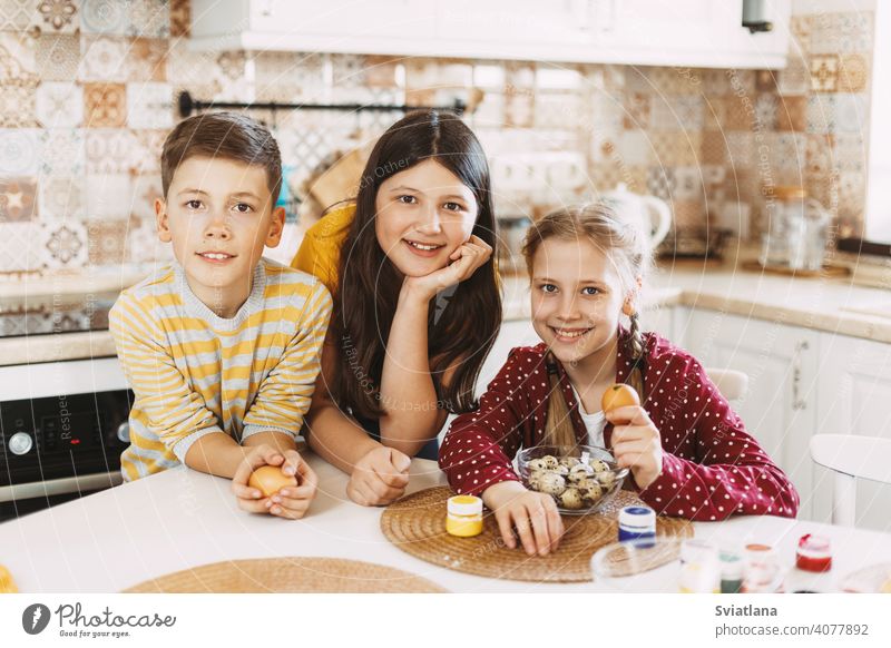 Funny and cheerful children sitting at the table paint Easter eggs in different colors for Easter easter spring holiday preparation sisters brother bright