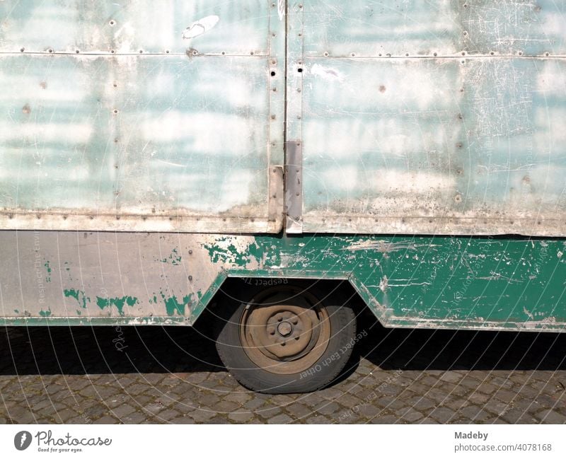 Converted old caravan with clear signs of use in the sunshine on the market place in Oerlinghausen near Bielefeld on the Hermannsweg in the Teutoburg Forest in East Westphalia-Lippe