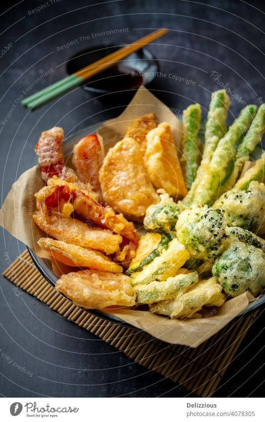 Side view of prepared Japanese vegetable tempura recipe with ginger ponzu sauce , black background with copy space appetizer bamboo bowl broccoli carrot