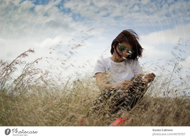 Woman sitting in the grass, hair blowing in the wind, in a state of relaxation. more adult pretty Beauty & Beauty Forest hairstyle Lifestyle naturally Nature