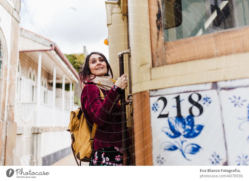 young caucasian backpacker woman sightseeing Porto views standing on a train. Travel concept travel city urban public transport yellow sun river spring