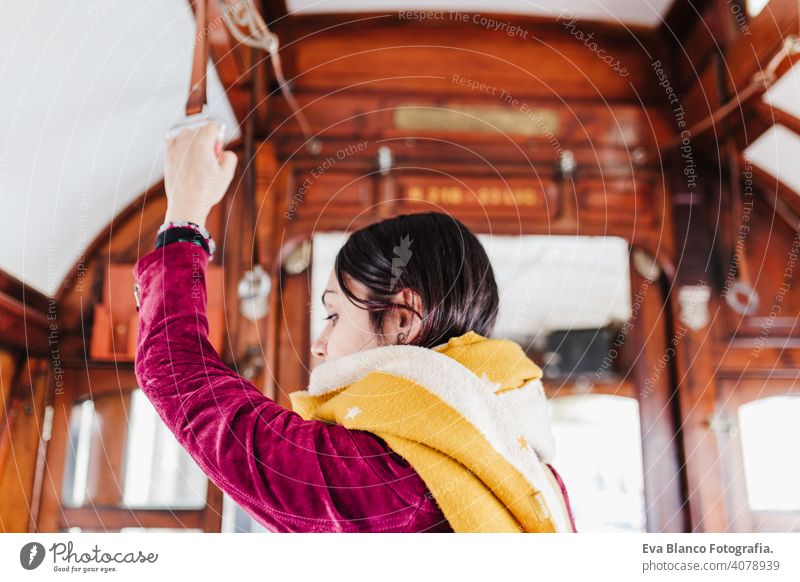 young caucasian backpacker woman sightseeing Porto views standing on a train. Travel concept travel city urban public transport yellow sun river spring