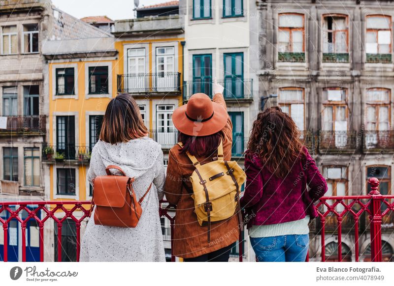 back view of three women sightseeing Porto views by the river. Travel and friendship concept mobile phone travel backpacker city urban sunset tourist tourism