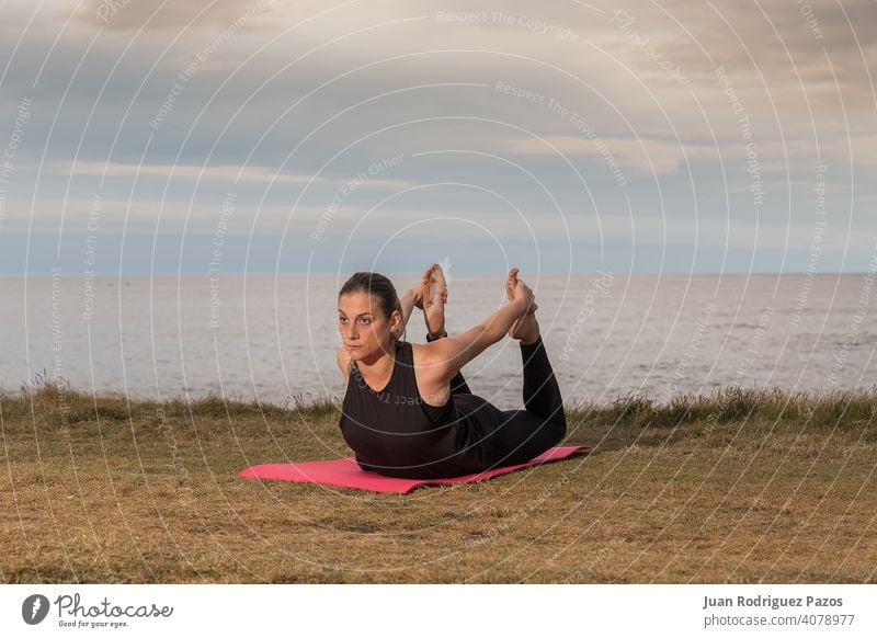 Woman in black sportswear exercising outdoors with the sea in the background. pilates yoga exercise healthy lifestyle woman mat stretching female fitness