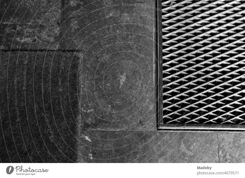 Grille with diamond pattern and doormat on the flagstones at the entrance of an old building in Braubachstraße in Frankfurt am Main in Hesse, photographed in classic black and white