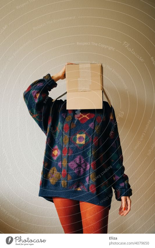 Woman in colorful clothes with a cardboard box on her head Cardboard Crate mail Order Anonymous Hide Exasperated Package variegated Carton Packaging Sweater