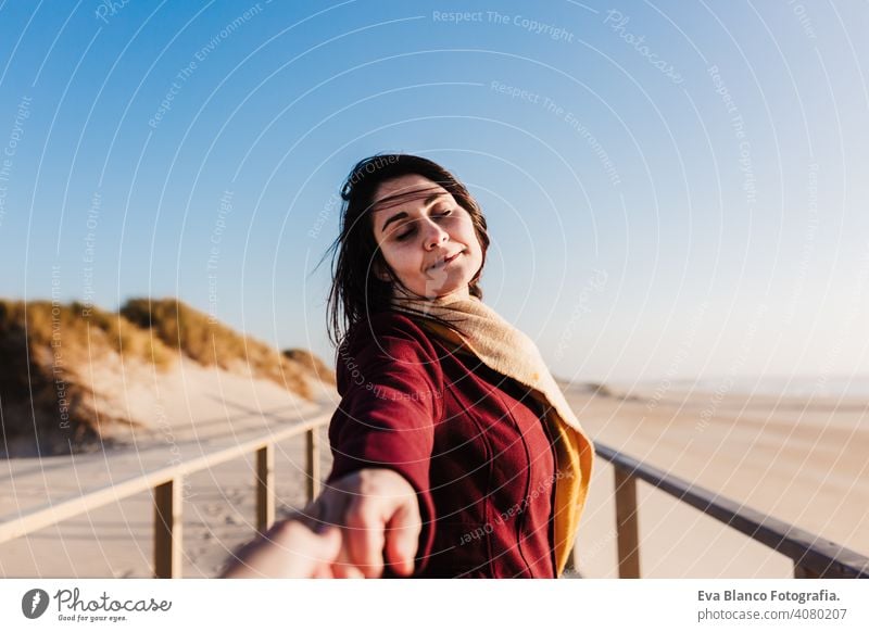 young caucasian woman with eyes closed relaxing at the beach at sunset. Holding hands with camera, follow me. Holidays and relaxation concept holding hands love