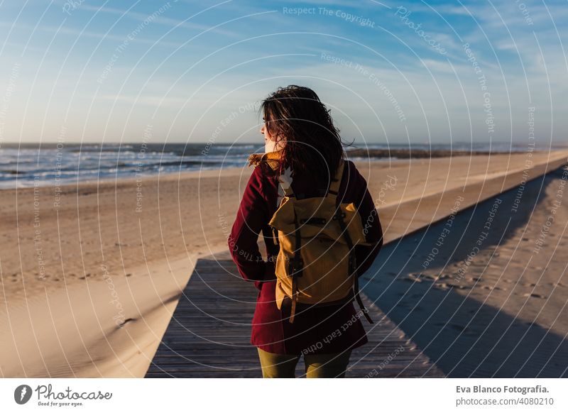 backpacker young caucasian woman relaxing at the beach at sunset. walking by wooden passage or runway. Holidays and relaxation concept vacation holidays