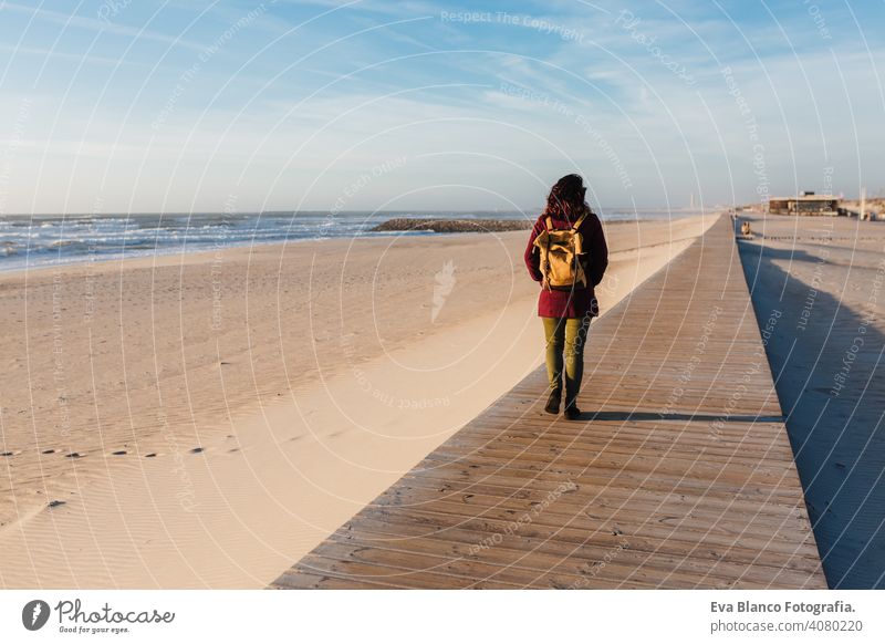 backpacker young caucasian woman relaxing at the beach at sunset. walking by wooden passage or runway. Holidays and relaxation concept vacation holidays