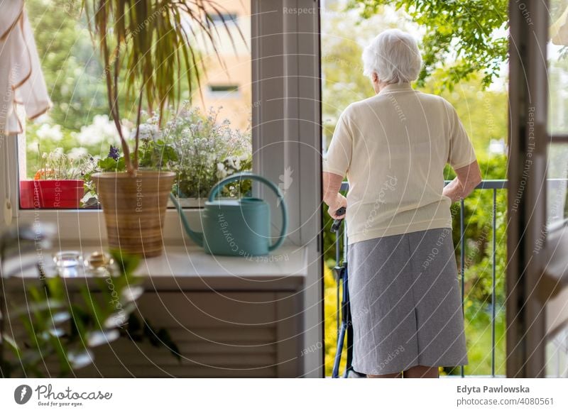 Senior woman with mobility walker standing on her balcony people senior mature casual female Caucasian elderly home house old aging domestic life grandmother