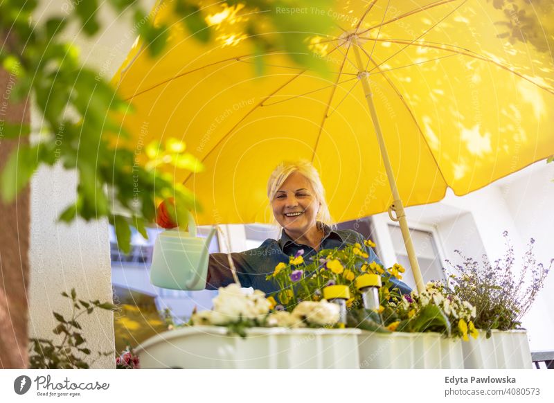 Senior woman taking care of her plants on the balcony smiling happy enjoying positivity vitality confidence people senior mature casual female Caucasian elderly