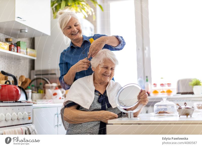 Woman cutting her elderly mother's hair at home smiling happy people woman senior mature female house old domestic life grandmother pensioner grandparent