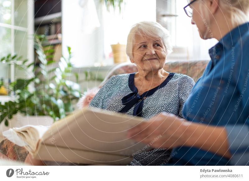 Granny showing her daughter memories from the past sitting memory nostalgia history photo album photos remember bonding two people family mother love together