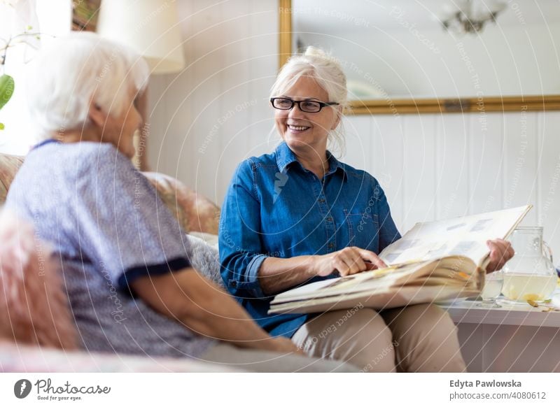 Granny showing her daughter memories from the past sitting memory nostalgia history photo album photos remember bonding two people family mother love together