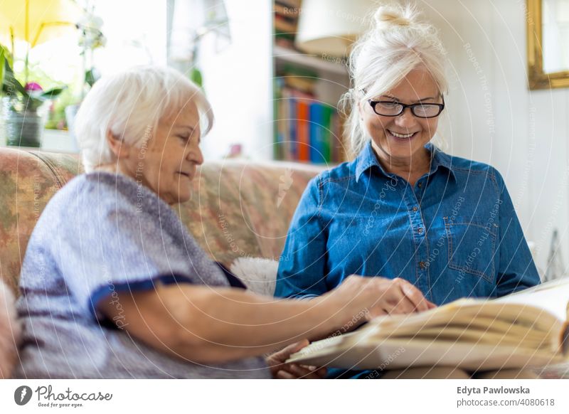 Granny showing her daughter memories from the past sitting memory nostalgia history photo album photos remember bonding two people family mother love together