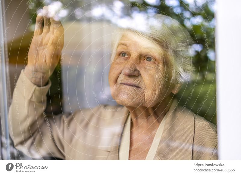 Senior woman looking out of window at home sad lonely unhappy depression uncertainty anxiety worried grief sadness loss problem crisis serious nostalgia