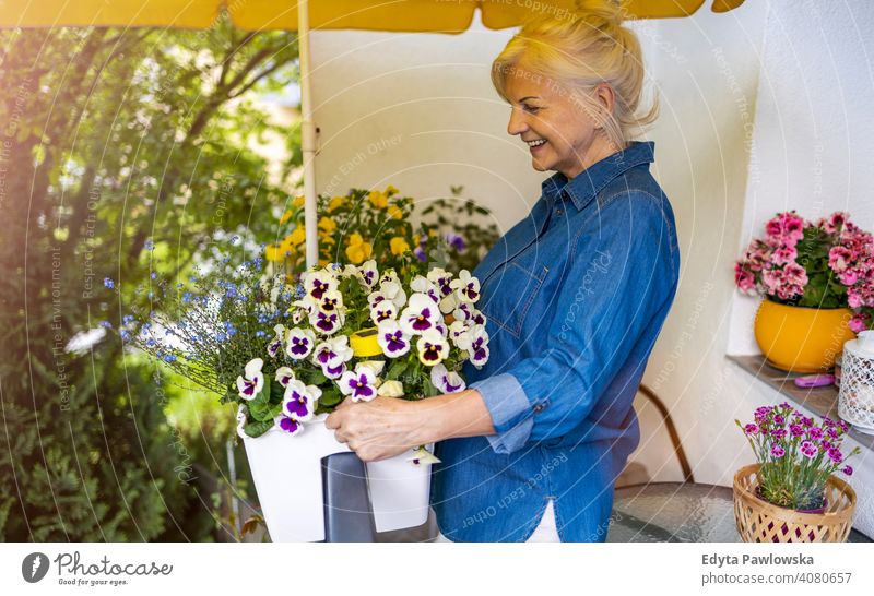 Senior woman taking care of her plants on the balcony smiling happy enjoying positivity vitality confidence people senior mature casual female Caucasian elderly