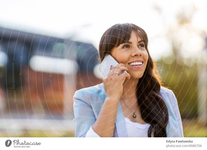 Attractive young woman using smartphone in the city hispanic latin smiling summer fun joy happy happiness urban girl people female lifestyle outdoors adult